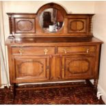 An early 20th Century oak Queen Anne revival sideboard, moulded pediment above a circular mirror
