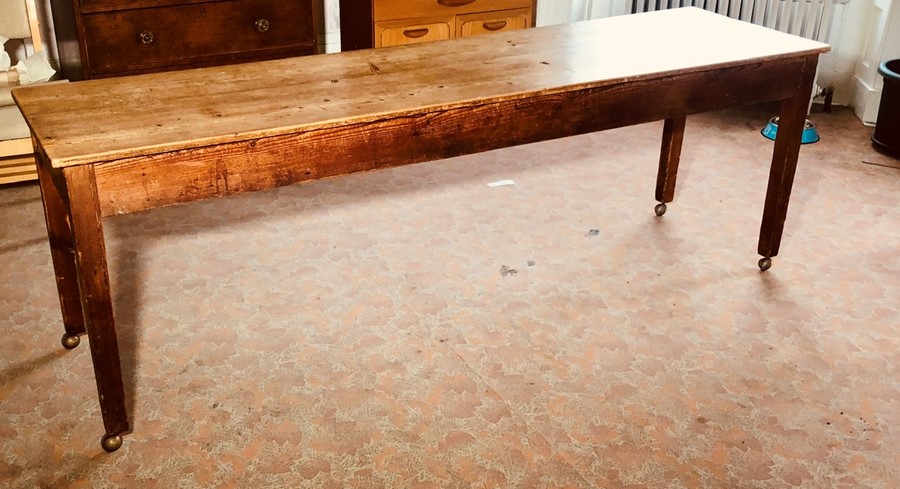 An early 20th century pine farmhouse kitchen table on later castors. 74cm H x 223cm L x 61cm W