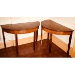 A pair of George III mahogany demi-lune tables, circa 1790, in Hepplewhite form, raised on tapered