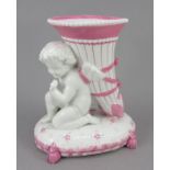 A late nineteenth century continental porcelain figure, possibly German of a cherub holding a