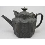 An early nineteenth century black basalt teapot and cover, c.1810. It has a hinged lid, flower and