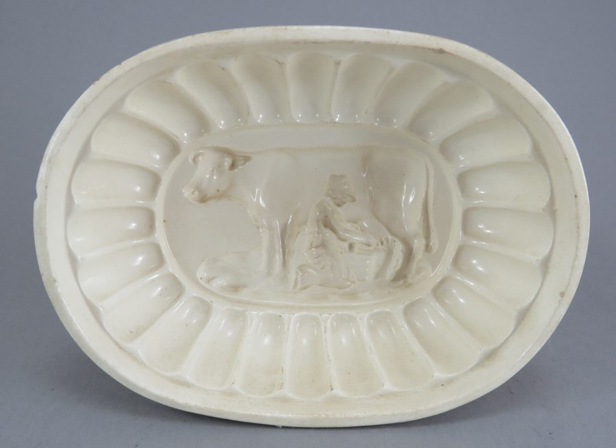 An early nineteenth century creamware jelly mould, c. 1820. It depicts a milkmaid and a cow. 18 cm