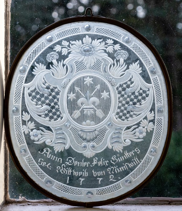 A late 18th Century German oval etched glass panel, scrollwork heraldic crest containing crossed
