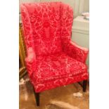 A George III revival wingback armchair, red tapestry upholstery with splay scrolling arms, raised on