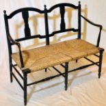 An Arts and Crafts ebonised two seater Sussex chair, in the manner of Morris & co, globe finials