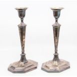 A pair of Edwardian silver candlesticks tapering stems on octagonal bases, engraved with a crest,