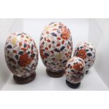 A collection of four Modern Japanese Satsuma graduating decorative eggs, on stands, each painted
