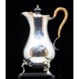 A George V silver pear shaped hot water jug, on raised trefoil feet, the cover with ebonised