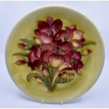 Moorcroft: A Walter Moorcroft 'Freesia' pattern plate on a pale yellow ground. Diameter 26cm approx.