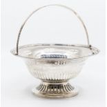 An Edwardian silver circular swing handle basket, beaded border above reticulated body, on similar