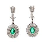 A pair of emerald and diamond 18ct white gold drop earrings, comprising a claw set oval emerald