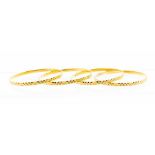 A collection of four high carat gold bangles, Indian origin, each with identical machine cut