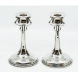 Liberty & Co. a pair of Cymric silver candlesticks, each with three sinuous supports, spreading