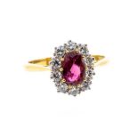 A ruby and diamond 18ct gold cluster ring, oval claw set ruby to the centre approx 7 x 5mm, within a