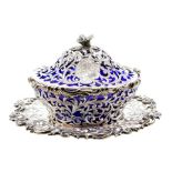 A Victorian shaped circular silver butter dish, cover on stand with blue glass liner, the stand with