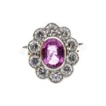 A pink sapphire and diamond platinum cluster ring, comprising a central oval cut sapphire approx 1.