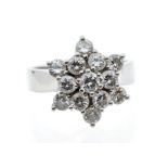 A diamond and platinum flower cluster ring, comprising thirteen graduated round brilliant cut