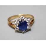 A sapphire and diamond ring, the central stone 6 x 5 mm within a border of diamonds on an 18ct