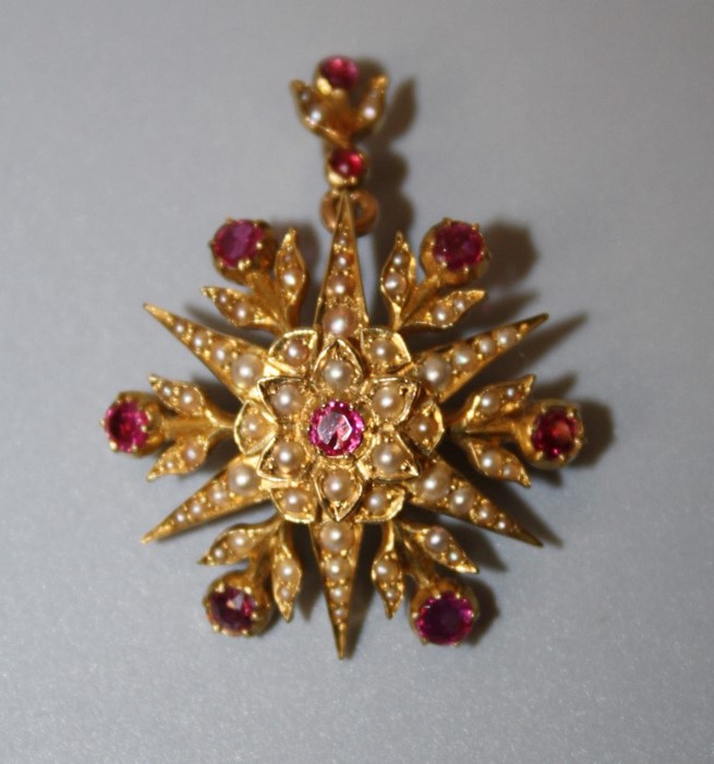 A late Victorian ruby and seed pearl brooch cum pendant, the six point star set with circular cut