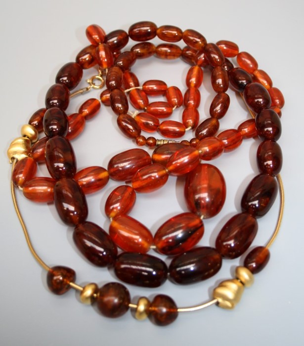 A graduated string of Amber type beads together with one other string of amber type beads. Note: