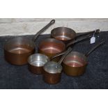 A set of six early 20th century French copper saucepans, each with pierced iron handle. The