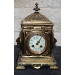 A late 19th century French brass mantle clock, the heavily cast architectural form case with mask