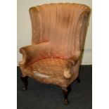 An Edwardian barrel back fireside armchair with serpentine fronted overstuffed seat on cabriole