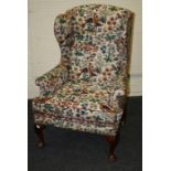 A Queen Anne style wing back fireside chair on cabriole supports.