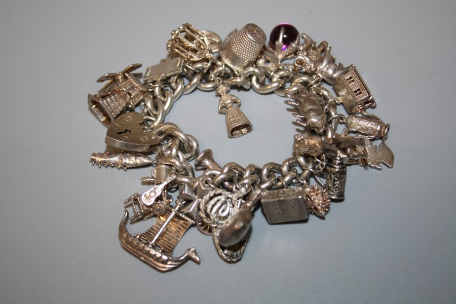 A 20th century silver charm bracelet affixed with 33 charms: dolphin, tennis racket, thimble,