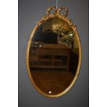 A Regency giltwood and gesso wall mirror with ribbon tied reeded oval frame and plain plate. 102 x