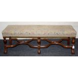 A 20th century walnut framed long stool, the bird and floral tapestry upholstered top on baluster