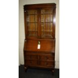 A 1930's oak bureau bookcase, the upper section with leaded glazed doors enclosing three shelves,