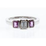 A pink sapphire and diamond three stone 18ct white gold ring, comprising a central emerald cut