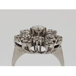 An 18ct. white gold diamond cluster ring, set single round brilliant cut diamond to centre with