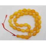 A string of yellow amber beads, of oval form, each approx.length 18mm x diameter 14mm, with a larger