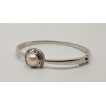 A precious white metal, diamond and cultured pearl hinged bracelet, the centre set single cultured