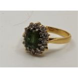 An 18ct. gold, peridot and diamond ring, set mixed cut peridot to centre bordered by round cut