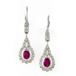 Pair of ruby drop earrings 18 kt white gold, each set with an oval ruby surrounded by small