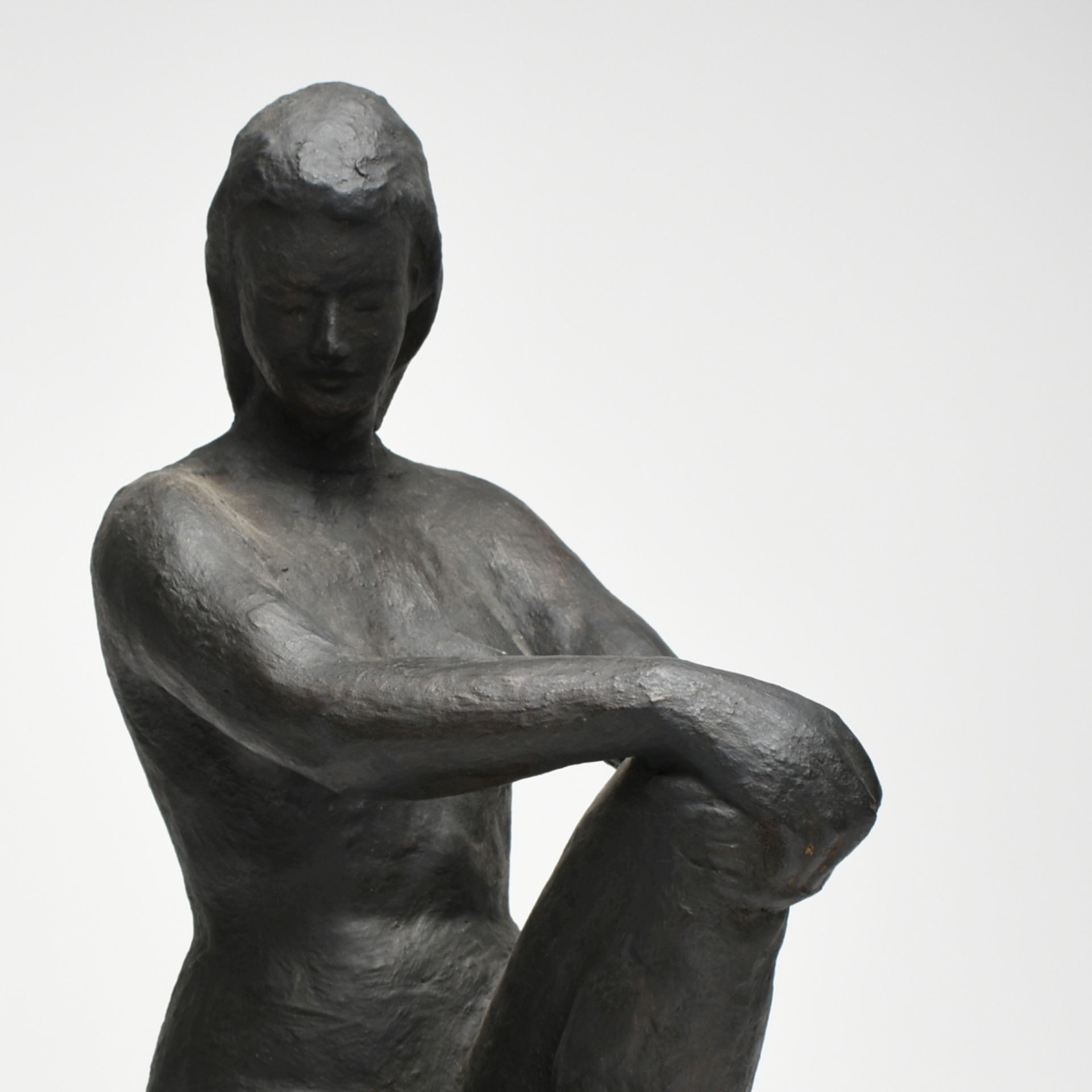 Aktfigur Terrakotta, schwarz gefasst, aufrecht sitzende Dame als Akt, beide Hände auf dem linken