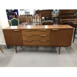 Art & Design: Post war teak sideboard with three long drawers, and cupboards either side.