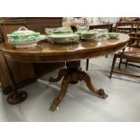 Victorian rosewood tilt top oval dining table on a baluster pedestal and four scrolled feet. 56¾