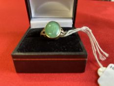 Jewellery: Yellow metal ring set with an oval Jade centre, with a rose cut diamond either side,