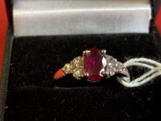 Jewellery: White metal ring, set with an oval cut ruby, estimated weight of 1·00ct. with three