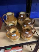 Doulton Lambeth: Stoneware harvest jugs. Six graduated jugs. Two A/F. From 5ins. to 8¼ins.