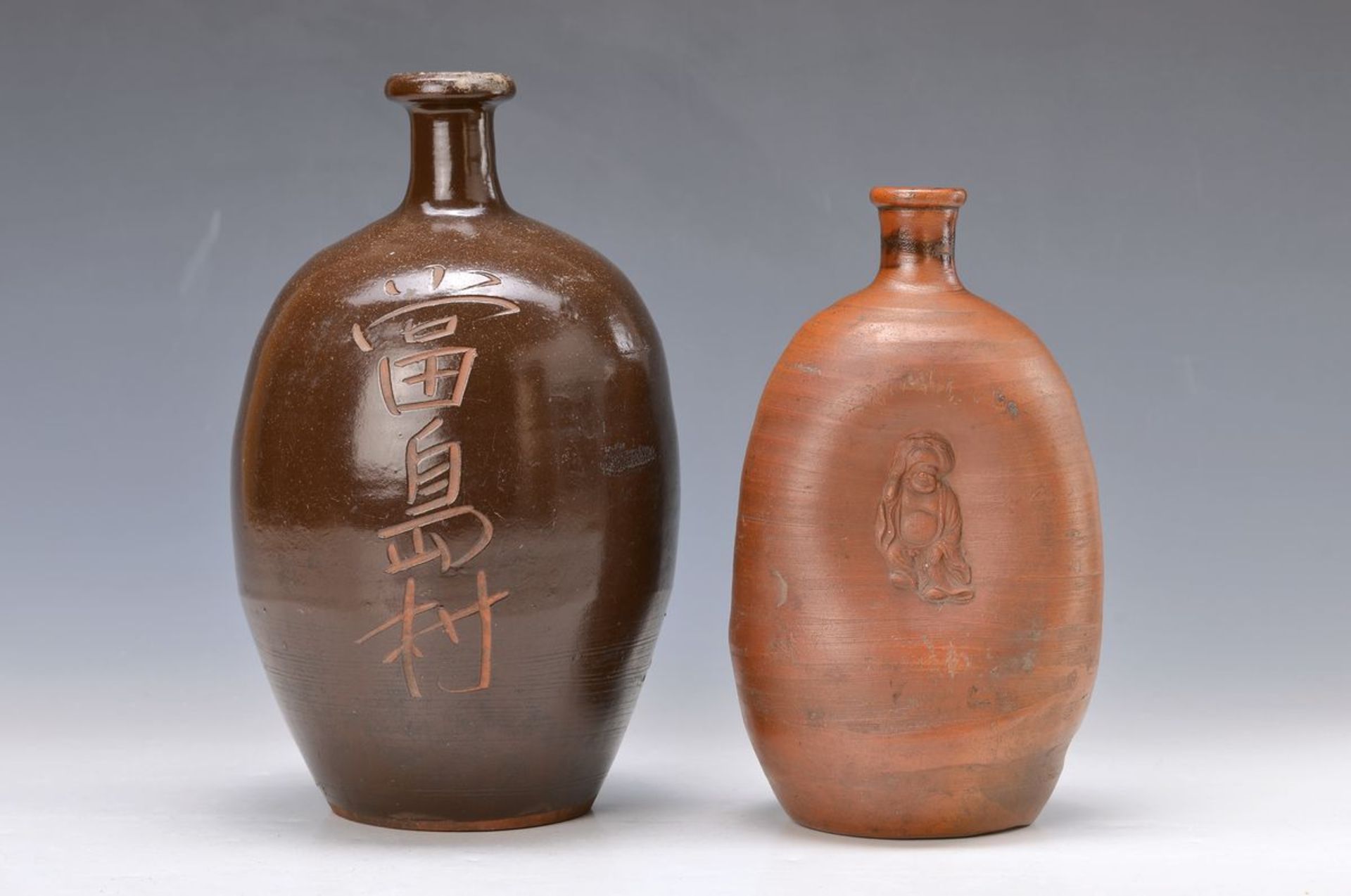 2 Sakeflaschen, Japan, stoneware, one with Hotei-decor, around 1900 and one of 20th c., Temucu-