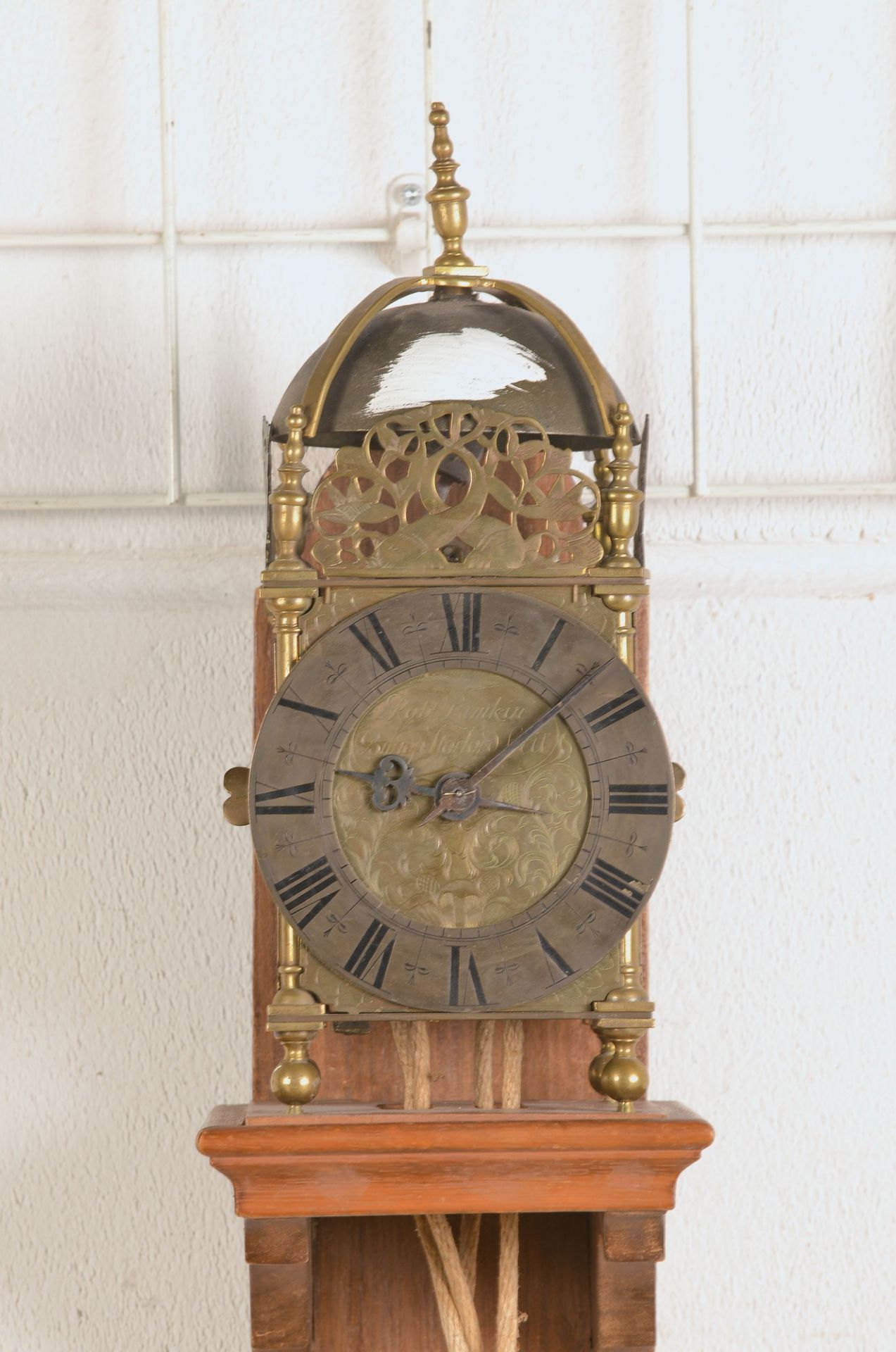 Lantern clock, after 1900, on wooden wall holder, brass housing, dial marked: Robt. Lunkin, Bishog