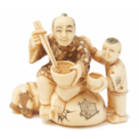AN IVORY FIGURINE MAN AND SON EATING