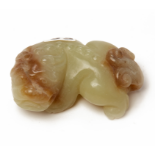 A SMALL CELADON AND RUSSET JADE CARVING OF A LION