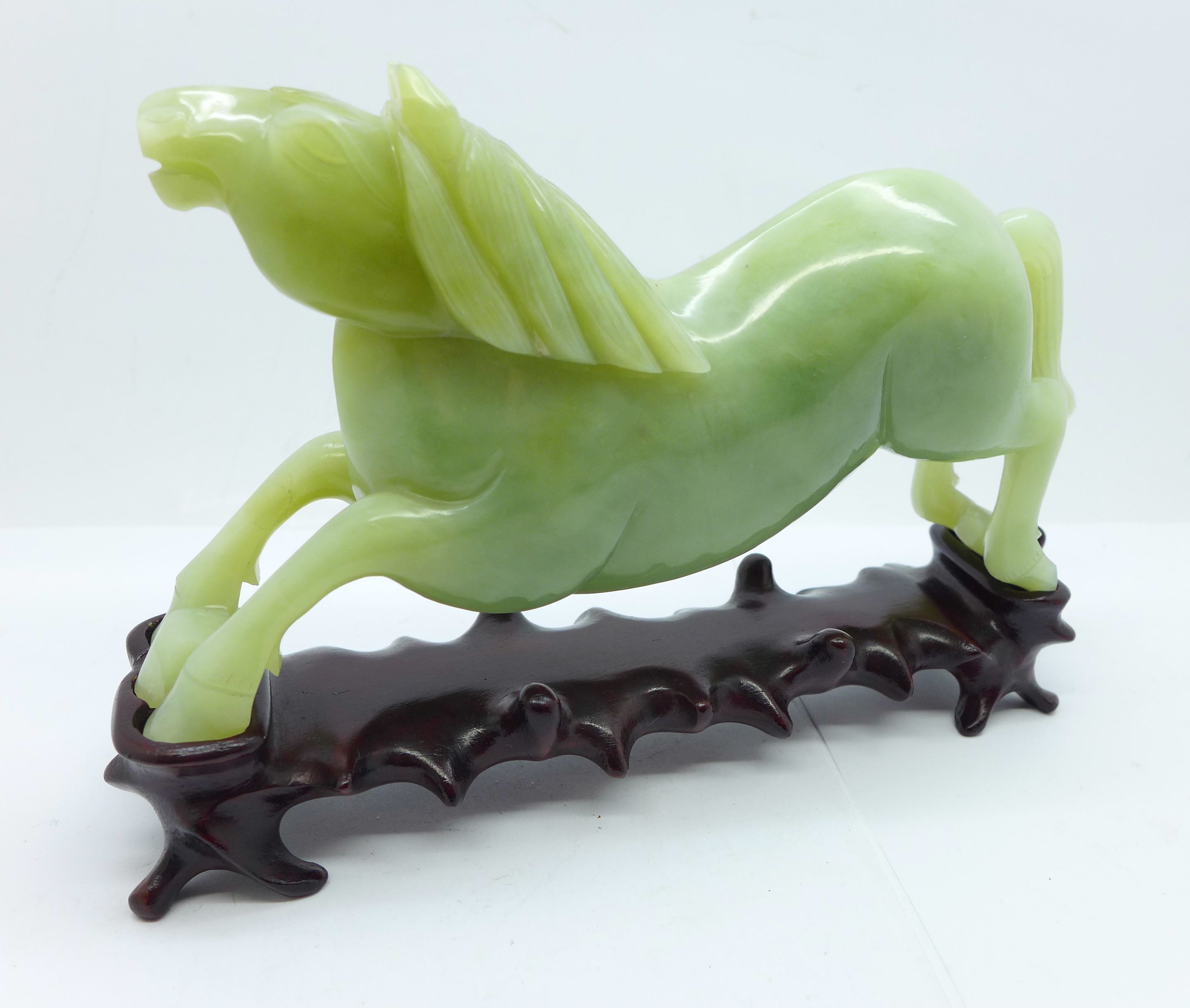 A Chinese carved jade figure of a horse, 18.5cm, on a wooden stand