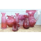 A large cranberry glass jug, three cranberry glass vases, mug and oversized brandy glass